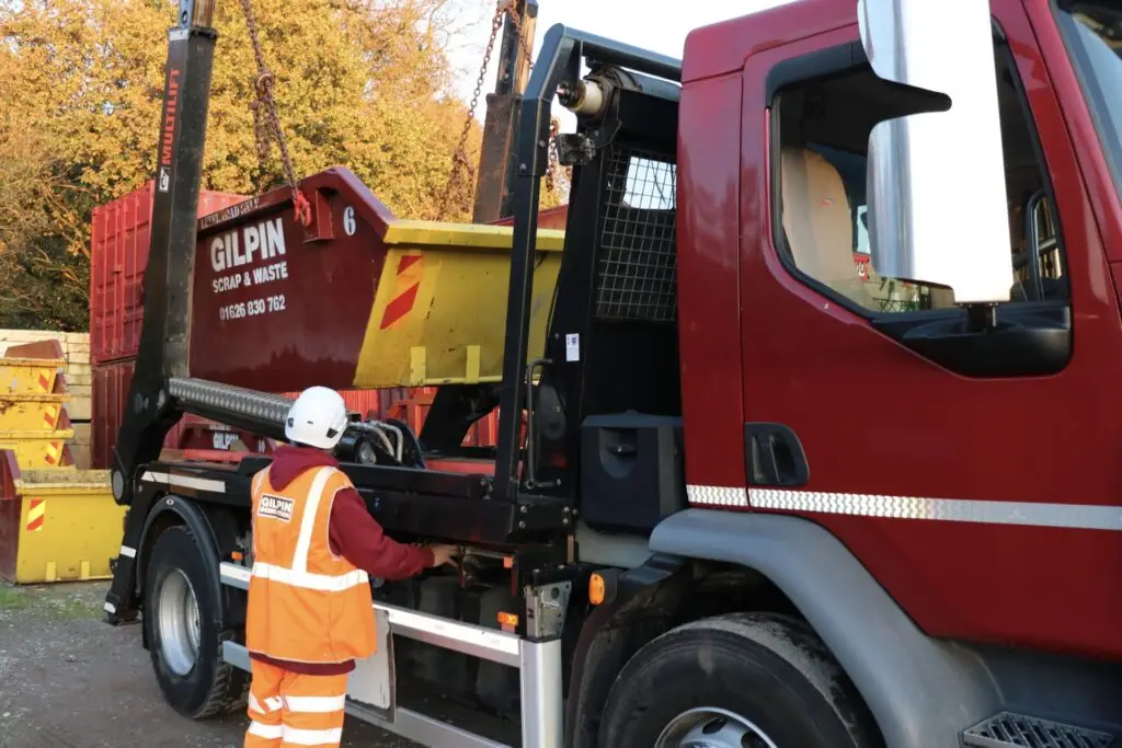operative loading 6 yard skip onto lorry for delivery